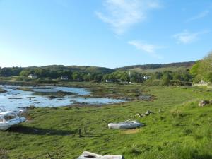 a boat sitting in a field next to a river at The Bellachroy Hotel in Dervaig