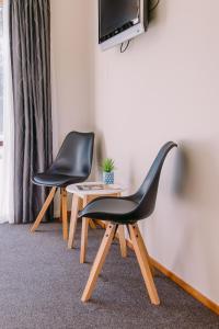 duas cadeiras pretas sentadas ao lado de uma mesa com uma televisão em Flaxbourne Motels em Ward