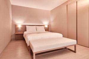 a bedroom with a large white bed and a bench at Tops10 Resort Donggang Cistar in Yeongwol