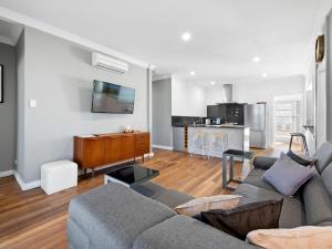 a living room with a couch and a kitchen at Salty Sea Cottage in Narooma +14 photos