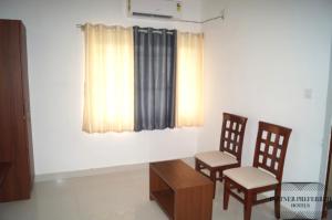 a room with two chairs and a table and a window at PPH Living BSK Deluxe in Bangalore