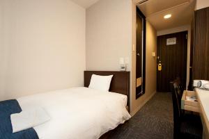 a hotel room with a white bed and a desk at Smile Hotel Asakusa in Tokyo