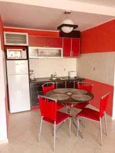 a kitchen with red walls and a table and red chairs at Apartament Onix in Neptun
