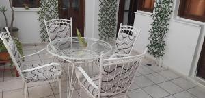 a glass table with four chairs and a vase on it at Villa Mare in Myrtos