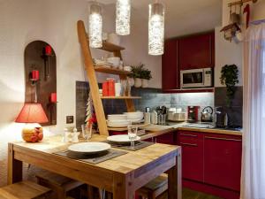 a kitchen with red cabinets and a wooden table at Studio Brides-les-Bains, 1 pièce, 4 personnes - FR-1-512-167 in Brides-les-Bains