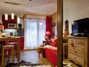 a bedroom with a red bed and a kitchen at Studio Brides-les-Bains, 1 pièce, 4 personnes - FR-1-512-167 in Brides-les-Bains