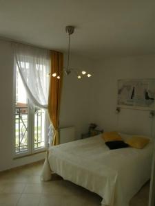 ein Schlafzimmer mit einem großen weißen Bett und einem Fenster in der Unterkunft ApartNet Apartamenty przy Promenadzie in Świnoujście