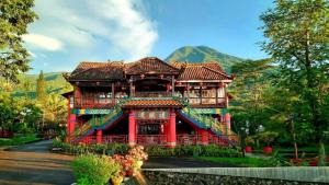 a large red building with a mountain in the background at Resort Highlander in Bogor