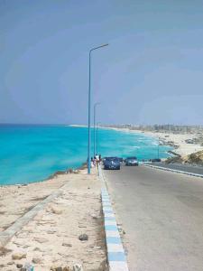 a road with a street light next to the ocean at Anglo Chalets - Ageeba beach in Marsa Matruh