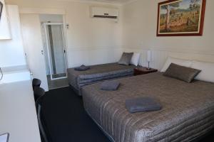 a hotel room with two beds and a mirror at Charleville Waltzing Matilda Motor Inn in Charleville