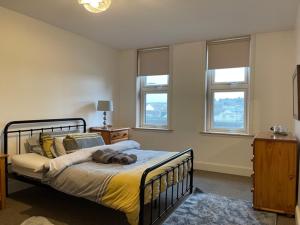 a bedroom with a bed in a room with windows at Centrally located 2 bed modern flat with harbour views in Wick