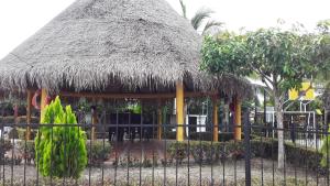 une cabane avec un toit de paille et une clôture dans l'établissement Acogedor y cómoda casa vacacional Condominios Flandes, à Flandes