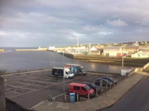 a parking lot with cars parked next to the water at Centrally located 2 bed modern flat with harbour views in Wick