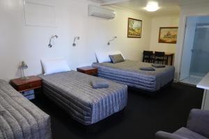 Habitación de hotel con 2 camas y mesa en Charleville Waltzing Matilda Motor Inn, en Charleville