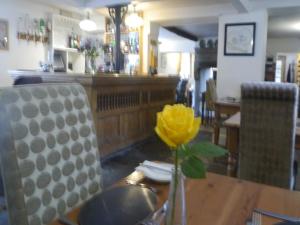 una flor amarilla en un jarrón sobre una mesa en 3 Millstones Inn en West Bradford