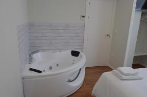 a white bathroom with a bath tub next to a bed at Apartamentos el Beyu in Cangas de Onís