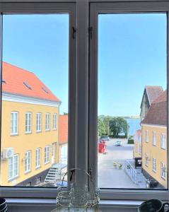 a window with a view of a street and buildings at Stege Torv Family Apartment in Stege