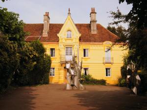 uma casa amarela com uma estátua em frente em Villa des Capucins em Luxeuil-les-Bains