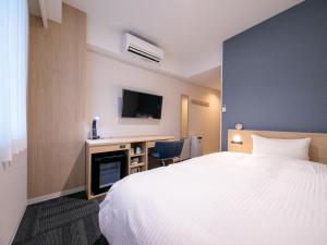 高知市にあるHotel Best Price Kochiのベッドとデスクが備わるホテルルームです。