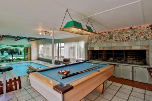 a pool table in a room with a swimming pool at Fisherhaven Travellers Lodge in Hermanus