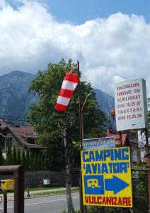 a flag on a pole next to a sign and a building at Camping Aviator Busteni, camere in Buşteni