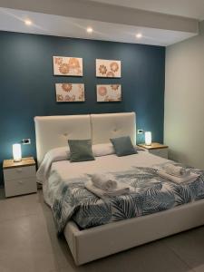 a bedroom with a white bed with a blue wall at Albergo Piazza Risorgimento in Porto Cesareo