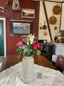 Kræmarvika Lodge في ترومسو: مزهرية مليئة بالورود تجلس على طاولة