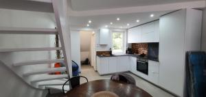 una cocina con armarios blancos, una mesa y una escalera en claire, en Camiers