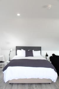 - une chambre avec un grand lit aux murs blancs dans l'établissement The Loft , Portrush, à Portrush