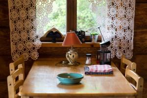 une table en bois avec une lampe et un bol sur celle-ci dans l'établissement Auru Cīruļi, à Auri