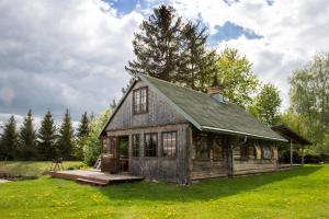 a house on a grass field with trees in the background at Auru Cīruļi in Auri