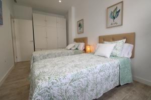 sypialnia z 2 łóżkami i lampką w obiekcie Del Parque Flats Puerto w Maladze