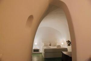 1 dormitorio con cama y puerta abovedada en Hiraeth Santorini, en Megalokori