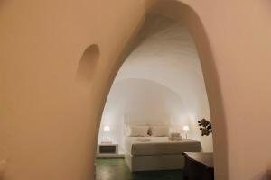 una camera con letto e porta ad arco di Hiraeth Santorini a Megalochori Altre 37 foto