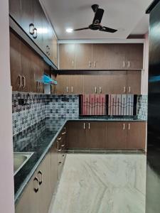 a kitchen with wooden cabinets and a ceiling fan at Temple stay - Uma Residency and Guest House in Mayiladuthurai