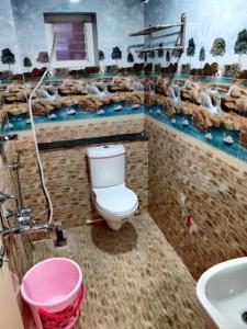 uma casa de banho com um WC e um lavatório com um mural em Temple stay - Uma Residency and Guest House em Mayiladuthurai