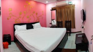 um quarto com uma cama grande e uma parede rosa em Temple stay - Uma Residency and Guest House em Mayiladuthurai