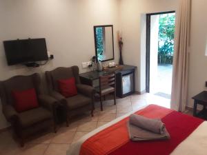 Dormitorio con cama, escritorio y TV en Forest Villa's, en St Lucia