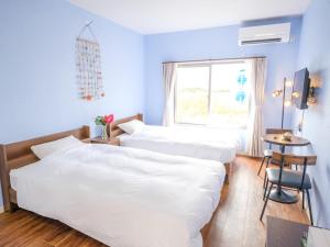 two beds in a room with a window and a table at Hotel Shion no Umi - Vacation STAY 98886 in Miyako Island