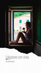 a woman sitting in a window with a cell phone at Antico Borgo di Torri in Sovicille