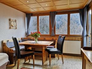 - une salle à manger avec une table, des chaises et des fenêtres dans l'établissement Appartements Duengler, à Schruns