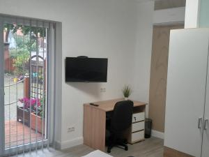ein Büro mit einem Schreibtisch und einem TV an der Wand in der Unterkunft Appartment Hochpaterre in Springe + 4 Fotos