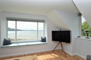 a living room with a flat screen tv next to a window at Greenlea in Strachur