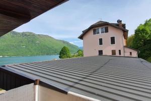 a house on the roof of a building next to a lake at Studio en bordure de Lac in Doussard