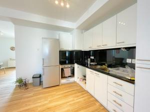a kitchen with white cabinets and a wooden floor at WSD Luxury Stylish 1BD Apt near Marina & Beach in Athens