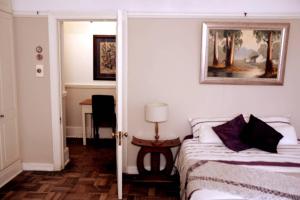 1 dormitorio con 1 cama y 1 mesa con lámpara en The Homestead - Simple Farm-Style Accommodation, en Port Alfred