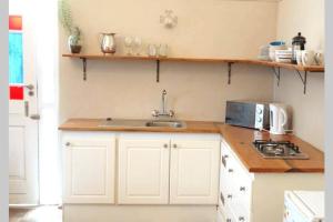 una cucina con armadi bianchi e lavandino di The Homestead - Simple Farm-Style Accommodation a Port Alfred