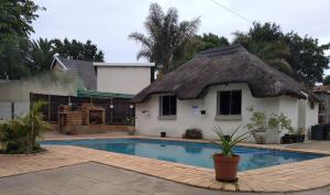 a house with a thatched roof and a swimming pool at Reizigers Rusten in Kempton Park