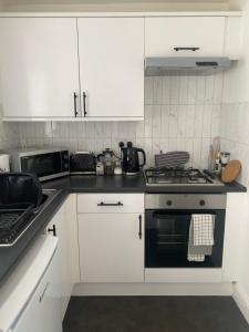 a kitchen with white cabinets and a stove top oven at Central Brighton garden studio, close to seafront in Brighton & Hove