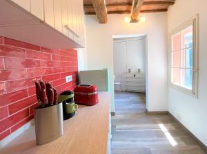 a kitchen with a red brick wall and a counter with knives at CAMPOREGIO 31- In Centro con Vista sul Duomo in Siena